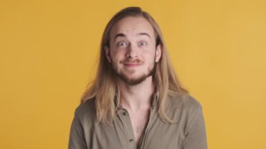 Şaşırmış sarışın berduşlu adam ellerini başının üstünde tutuyor. Renkli arka planda izole edilmiş gerçek dışı haberleri duymaktan gülümsüyor.