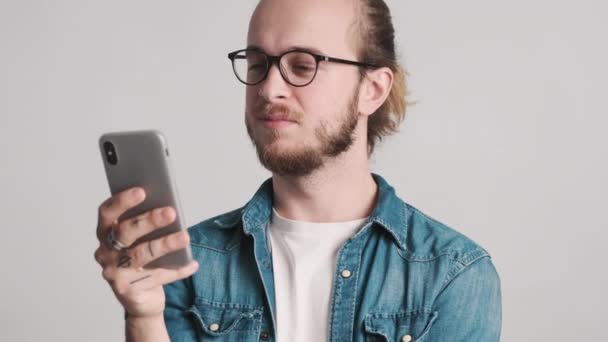 Привабливий Бородатий Хлопець Окулярах Переглядає Інтернет Сайти Смартфоні Білому Тлі — стокове відео