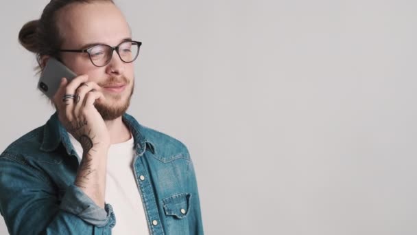 戴眼镜 留着胡子的年轻人穿着休闲装 在智能手机旁聊天 在白色背景上登广告 复制空间 — 图库视频影像