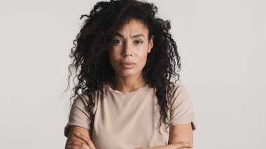 Siyah kabarık saçlı genç Afrikalı Amerikalı kadın beyaz arka planda izole edilmiş kamerada kızgın görünüyor. Kötü ruh hali ifadesi