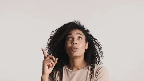 年轻的非洲裔美国女人 乌黑蓬松的头发 食指向上 在白色背景上展示广告的复制空间 — 图库照片