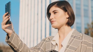 Modern iş kadını iş arkadaşlarıyla görüntülü konuşma yapıyor. Sokakta akıllı telefon kullanıyor. Modern teknoloji kavramı