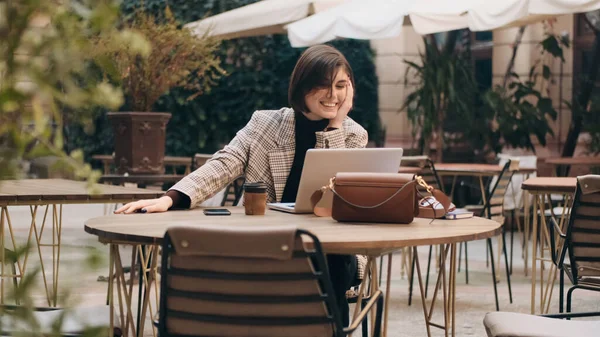 カフェの中庭でコーヒーブレイク中にラップトップを使用して家族と一緒にビデオ通話で幸せな話を見て若い陽気な実業家 — ストック写真