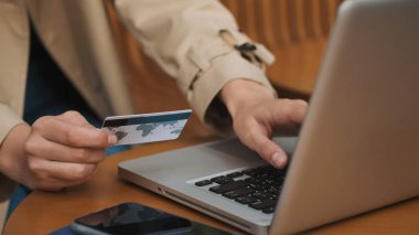 Bilgisayarda çalışan yakın plan kadın açık hava kredi kartıyla online alışverişleri ödüyor.