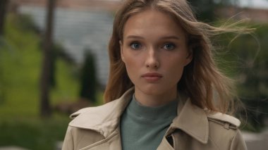 Sıradan giyinmiş çekici kız şehir parkında tek başına yürürken düşünceli görünüyor.