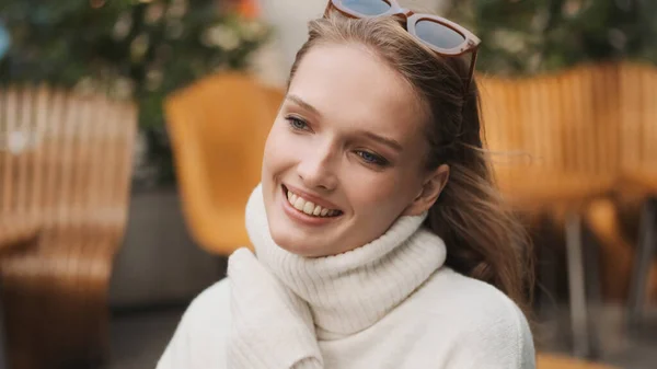 魅力的な笑顔の女の子の肖像画居心地の良い白い色のセーターを身に着けている幸せな通りのカフェで楽しい一日を見て — ストック写真