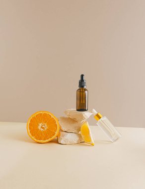 Gerçekten eşsiz bir natürmort. Toprak renkli arka planda damla şişesi ve narenciye meyvesi. Güzellik ve sağlık konsepti. Asgari estetik.