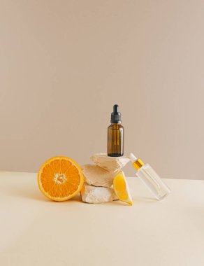 Gerçekten eşsiz bir natürmort. Toprak renkli arka planda damla şişesi ve narenciye meyvesi. Güzellik ve sağlık konsepti. Asgari estetik.