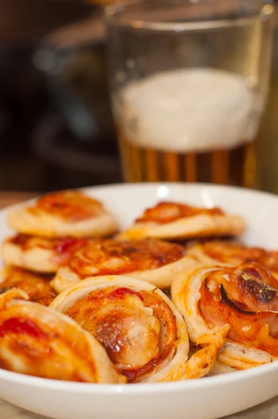 Pizza en un plato blanco con un vaso de cerveza — Foto de Stock