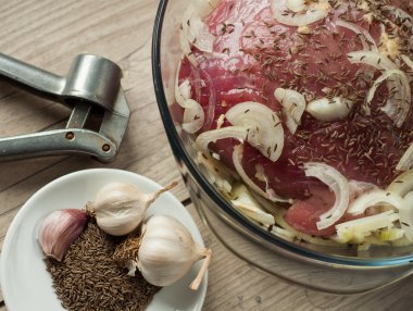 çiğ domuz eti et kavurma soğan kimyon ve ahşap masa üzerinde sarımsak ile