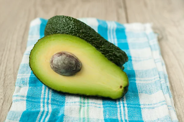 Halved avocados on rustic wooden background — Stock Photo, Image