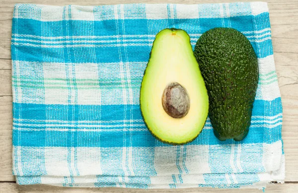 Halved avocados on rustic wooden background — Stock Photo, Image