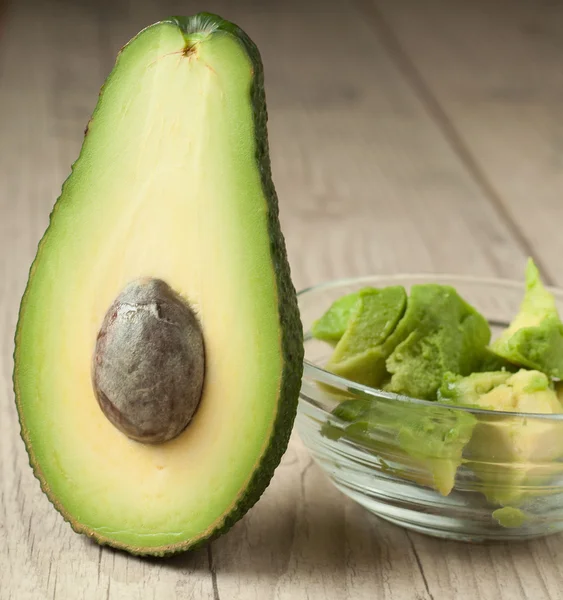 Halved avocados on rustic wooden background — Stock Photo, Image