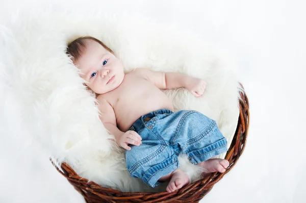 Adorable baby in jeans resting in a wicker basket — Stock Photo, Image