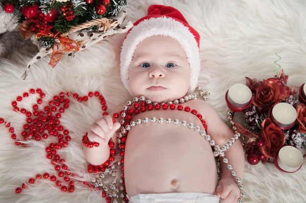 Lindo bebé en sombrero de santa acostado en la alfombra cerca del árbol de Navidad —  Fotos de Stock