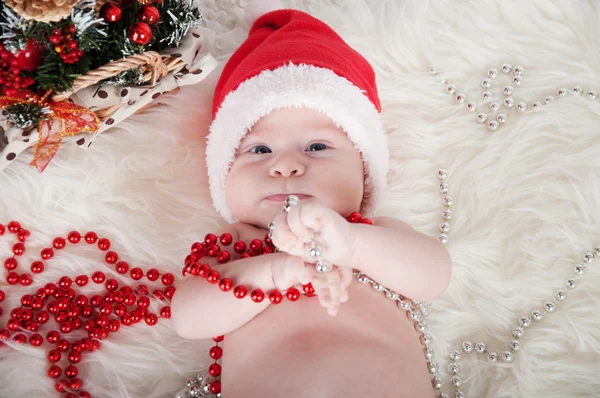 Söt baby i santa hatt ligger på mattan nära julgranen — Stockfoto