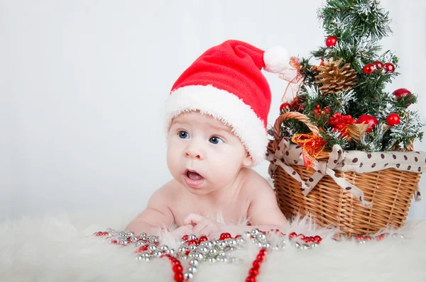 Lindo bebé en sombrero de santa acostado en la alfombra cerca del árbol de Navidad —  Fotos de Stock