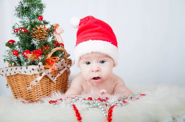 Lindo bebé en sombrero de santa acostado en la alfombra cerca del árbol de Navidad —  Fotos de Stock