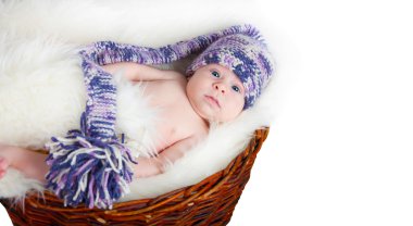 Newborn baby lies in basket in a multi color hat on white background. clipart