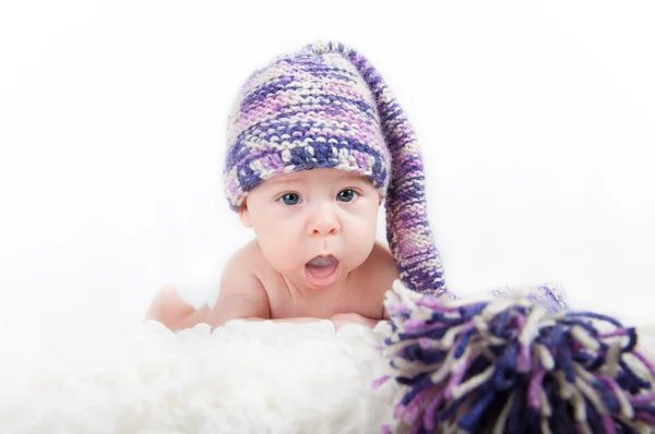 Neugeborenes Baby mit buntem lustigen langen Hut blickt in die Kamera — Stockfoto