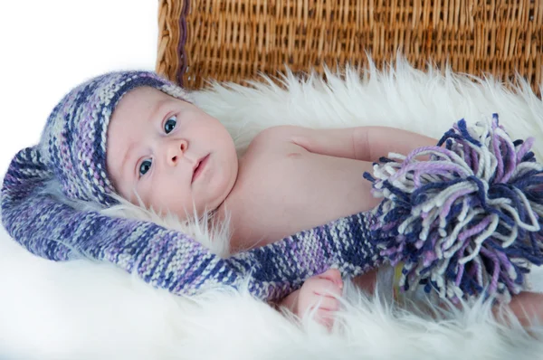 Nouveau-né se trouve dans le panier dans un chapeau multicolore sur fond blanc . — Photo