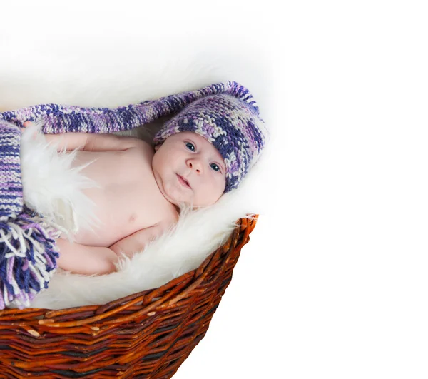 Nouveau-né se trouve dans le panier dans un chapeau multicolore sur fond blanc . — Photo