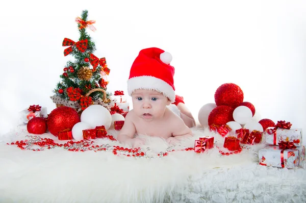 Lindo bebé en el sombrero de Santa con un árbol de Navidad detrás —  Fotos de Stock