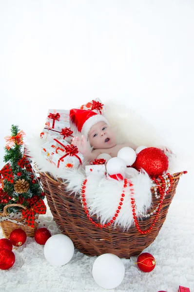 Funny baby dressed in Santa Claus hat on bright festive background — Stock Photo, Image