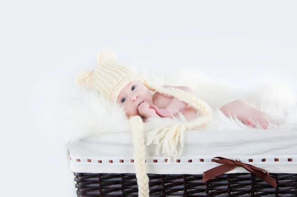 A cute little baby is looking into the camera and is wearing a white hat. The baby could be a boy or girl and has blue eyes. — Stock Photo, Image