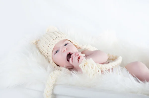 Um bebezinho bonito está olhando para a câmera e está usando um chapéu branco. O bebê pode ser um menino ou menina e tem olhos azuis . — Fotografia de Stock