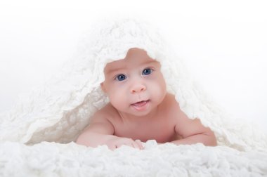 Çocuk bir battaniyenin altında yalan ve kameraya bakıyor