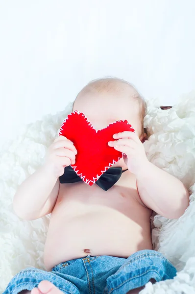 Liten vacker pojke i fluga och med rött hjärta — Stockfoto