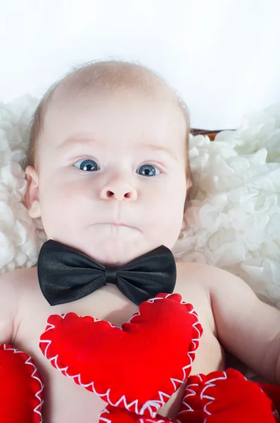 Pequeno menino bonito em gravata arco e com coração vermelho — Fotografia de Stock