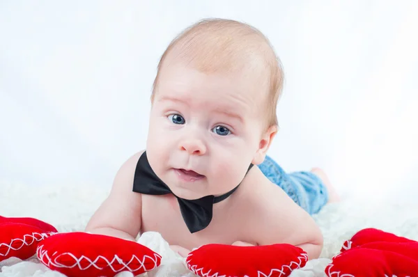 Liten vacker pojke i fluga och med rött hjärta — Stockfoto