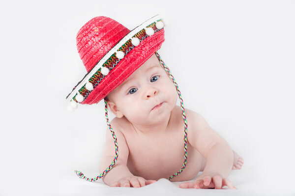 Cheerful little boy with a sombrero and maracas on a white background