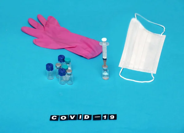 Covid-19 vaccine vials with face mask and glove with syringe ready for implementing