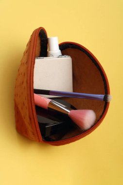 Deri, turuncu, açık güzellik çantası, fırçalar ve diğer makyaj malzemeleri.