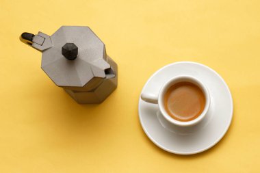 Espresso için geleneksel İtalyan kahve demliği ve sarı arka planda bir fincan kahve.