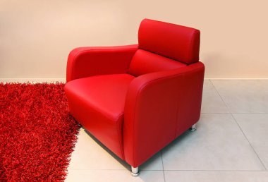 Kırmızı modern deri koltuk, içi boş yumuşak halıların yanında.