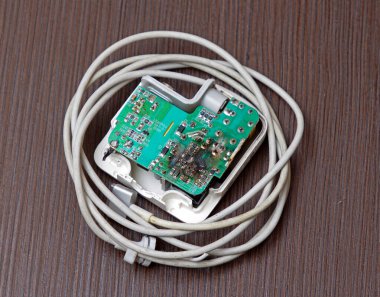 Kabloların yanında yanmış elektrik kartı olan modern bir dizüstü bilgisayar şarj cihazı.