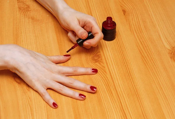 Manos Femeninas Sobre Mesa Madera Pintando Clavos Con Esmalte Rojo —  Fotos de Stock