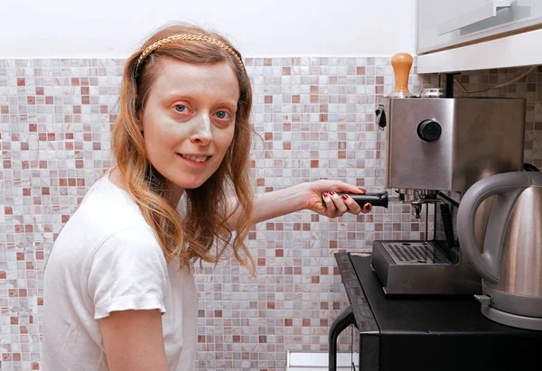 ホームキッチン内のエスプレッソマシンでコーヒーを作る若い女性 — ストック写真