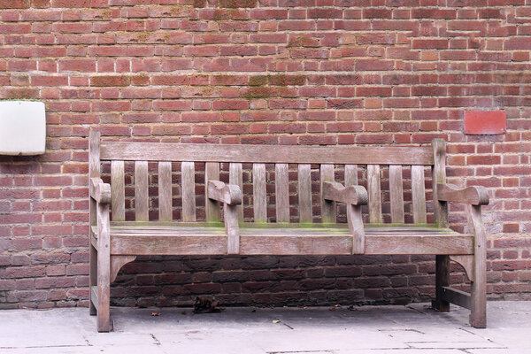 Retro wooden bench with brick wall in background
