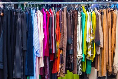 Mağazanın içindeki metal bir rafta asılı modern renkli kadın kıyafetleri.