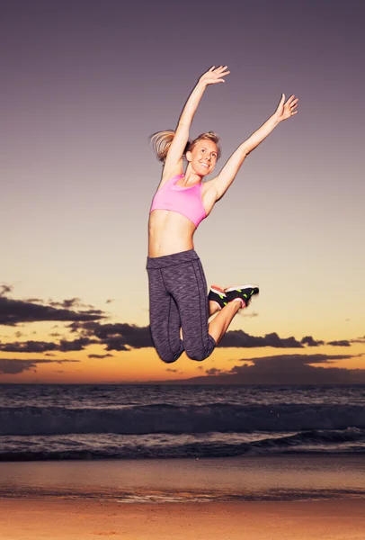 Женщина прыгает по пляжу на закате — стоковое фото