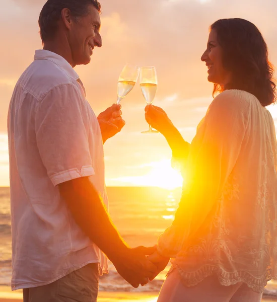 Par njuter av glas champene på stranden vid solnedgången — Stockfoto