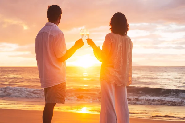 Пара, насолоджуючись скло champene на пляжі на заході сонця — стокове фото