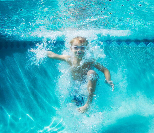 Мальчик ныряет под воду в бассейне

