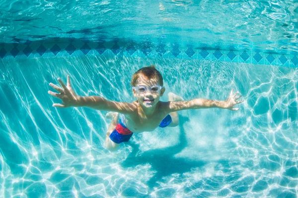 Jovem menino mergulho subaquático na piscina — Fotografia de Stock