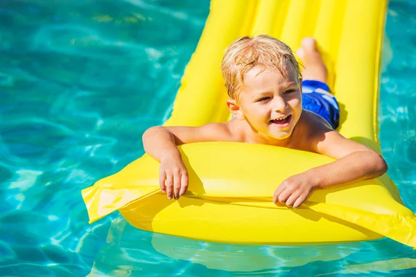 Jongen ontspannen en plezier in zwembad op gele vlot — Stockfoto